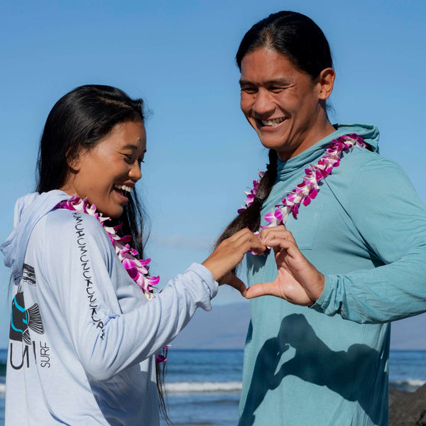 Man and woman wearing Humu Woody Bamboo Lightweight Hoodies in marine blue and light blue beside the ocean
