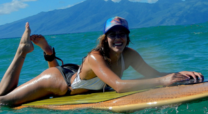 Woman relaxing on a paddleboard wearing the Humu Surf Napili Truckers Hat