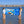 Load image into Gallery viewer, Two women wearing Humu Surf apparel and trucker hats holding the blue Live With Aloha Yoga Towel in shallow ocean water, displaying colorful tropical fish artwork and Humu Surf branding
