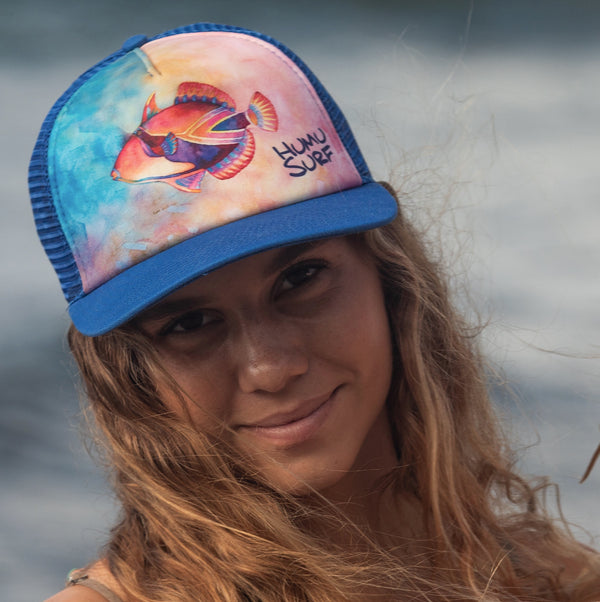 Woman wearing the colorful Humu Napili Trucker Hat with royal-blue bill and mesh back