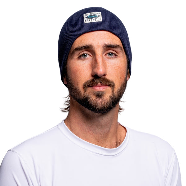 Front portrait of a man wearing the Navy Humu Surf Beanie with embroidered fish logo patch
