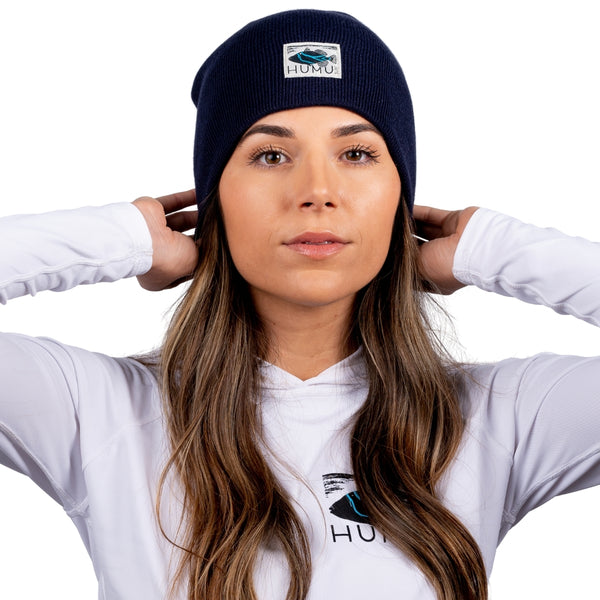 Woman wearing the Navy Humu Surf Beanie with embroidered fish logo patch