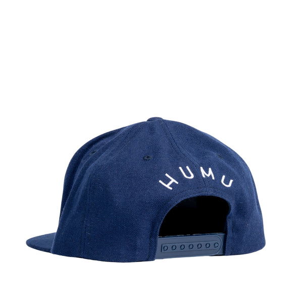 Rear three-quarter view of the navy Humu Wave Snapback Cap showing the adjustable snap closure