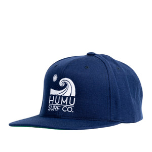 Three-quarter view of the navy Humu Wave Snapback Cap with embroidered Humu Surf Co. wave logo